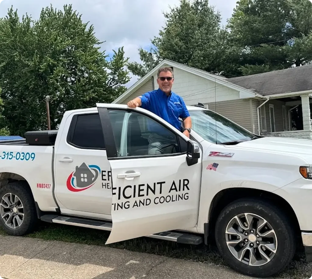 A man in a blue shirt stands beside an open door of a white pickup truck labeled “Efficient Air Heating and Cooling” parked in front of a house.